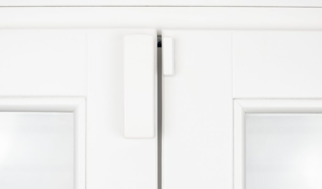 A window and door contact sensor on a white wooden sash.